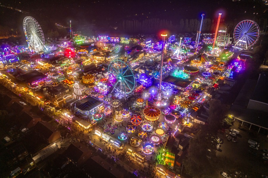 An aerial view of a busy fairground at night, with many lights