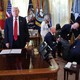 President Donald Trump stands by as attendees help a guest after he collapsed during an event in the Oval Office.