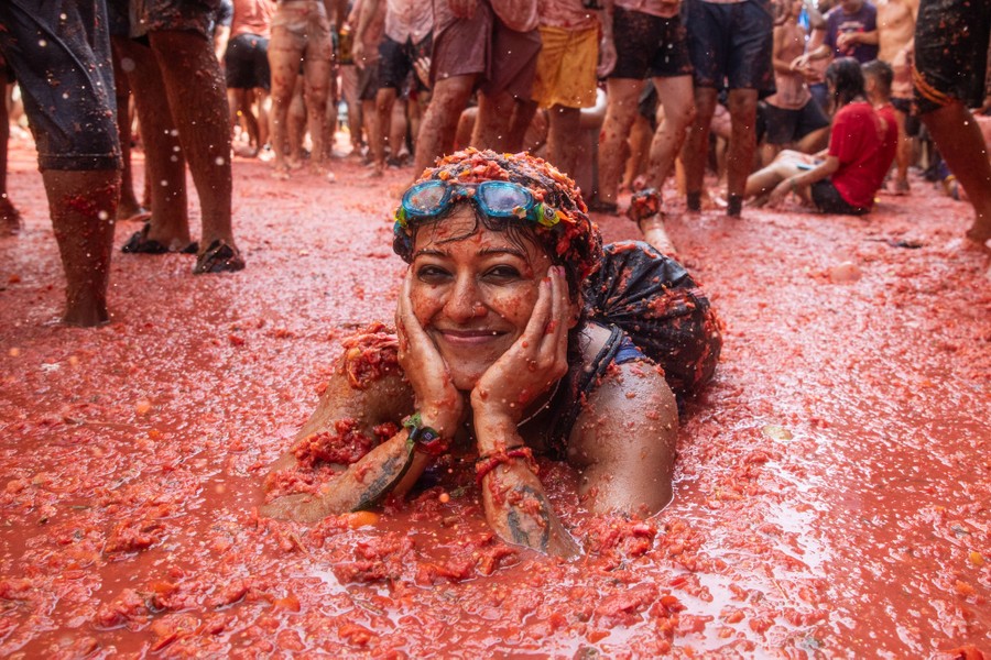 A person lies down in a tomato-and-water soup that has formed after a large bout of tomato-throwing.