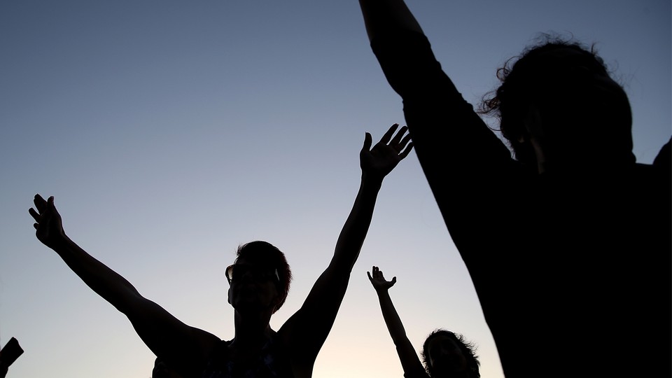 Silhouettes of people praying with their arms stretched up and out