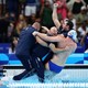 Coaches and a member of a water-polo team celebrate, embracing and falling into a pool together.