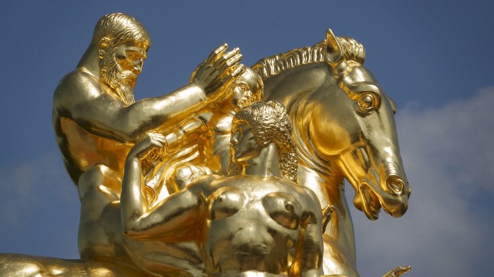 The Arts of War Sacrifice and Valor gold-leaf-covered bronze statue is shown against a blue sky.