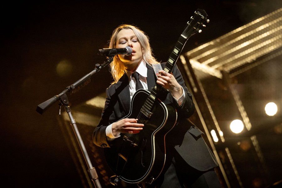 A singer performs, playing a guitar.