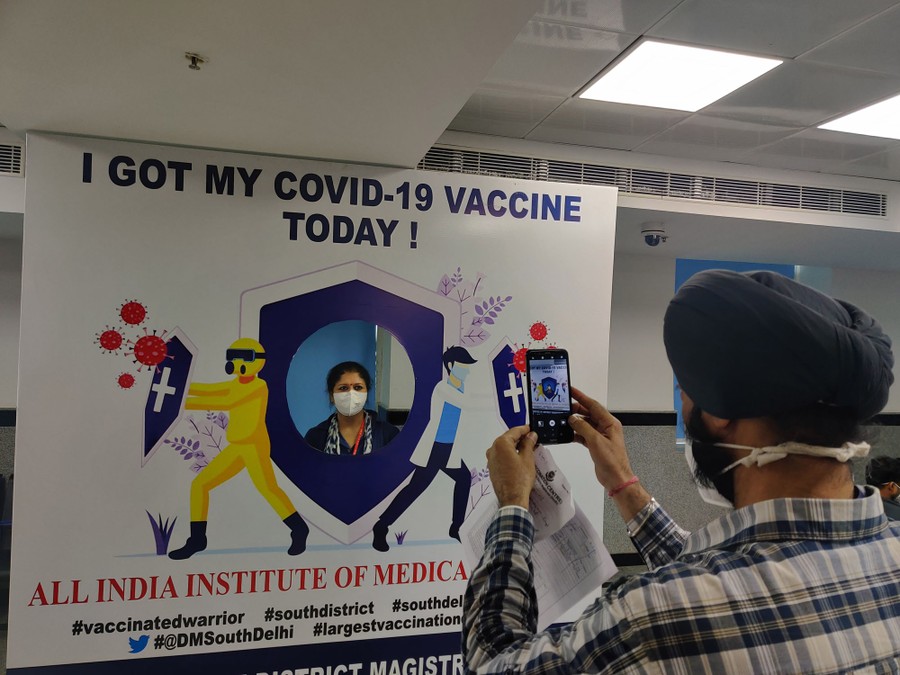 A person poses for a photo behind a large sign that reads "I Got My COVID-19 Vaccine Today!"