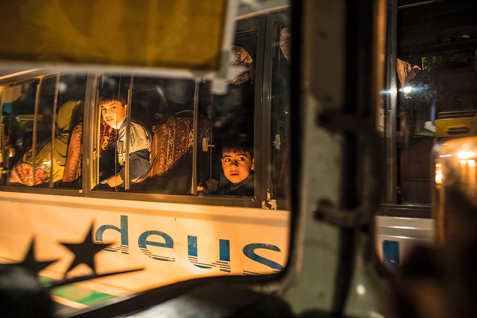 Children looking out a bus window at night