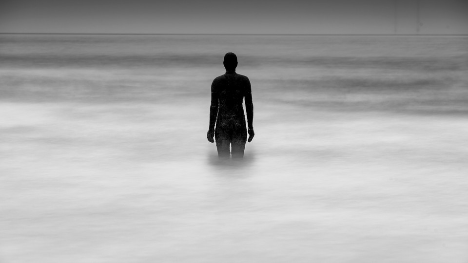 Statute of a man standing in the middle of the water covered with fog