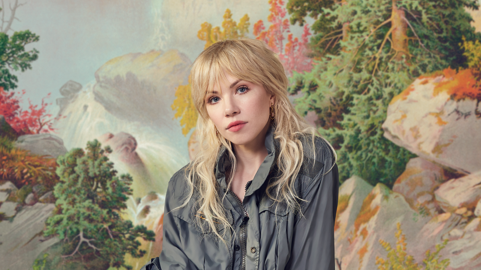 Carly Rae Jepsen against a pastel forest background