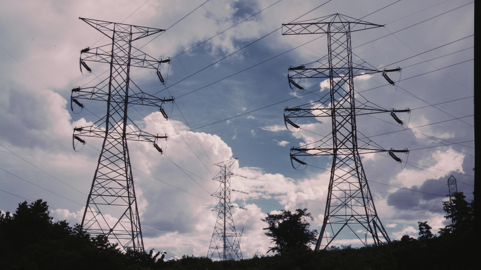 An image of transmission lines sitting atop two large metal structures