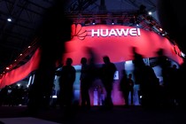 Visitors walk past a Huawei stand at the 2017 Mobile World Congress in Barcelona, Spain.