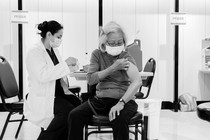 Black-and-white photo of a woman receiving a COVID-19 vaccine