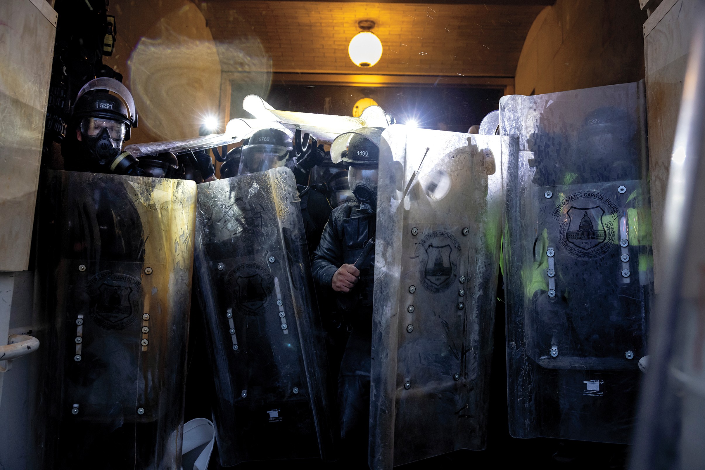 photo of police in full riot gear with helmets and shields standing across concrete tunnel 