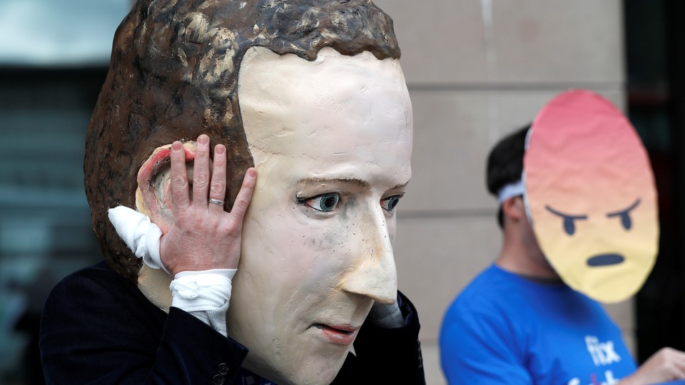 A demonstrator wears a giant mask of Facebook CEO Mark Zuckerberg.