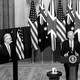 The U.S. president stands alongside the leaders of Australia and Britain on video screens.