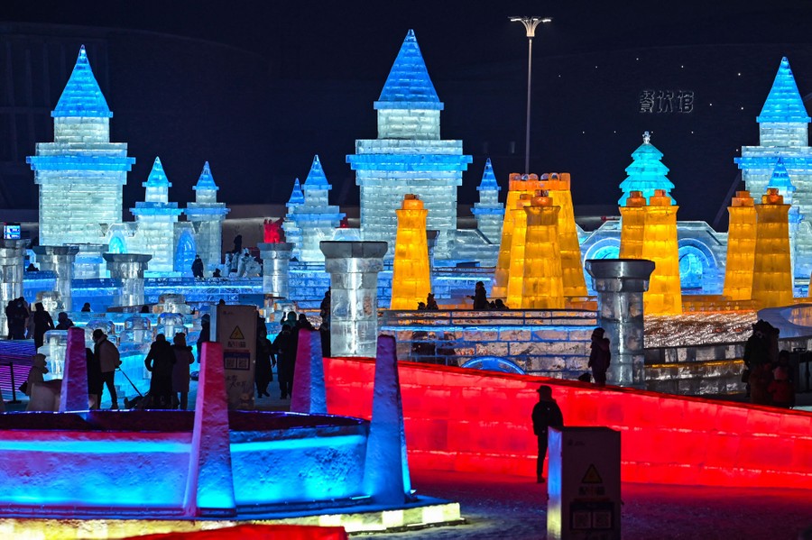 People gather among many illuminated ice sculptures.