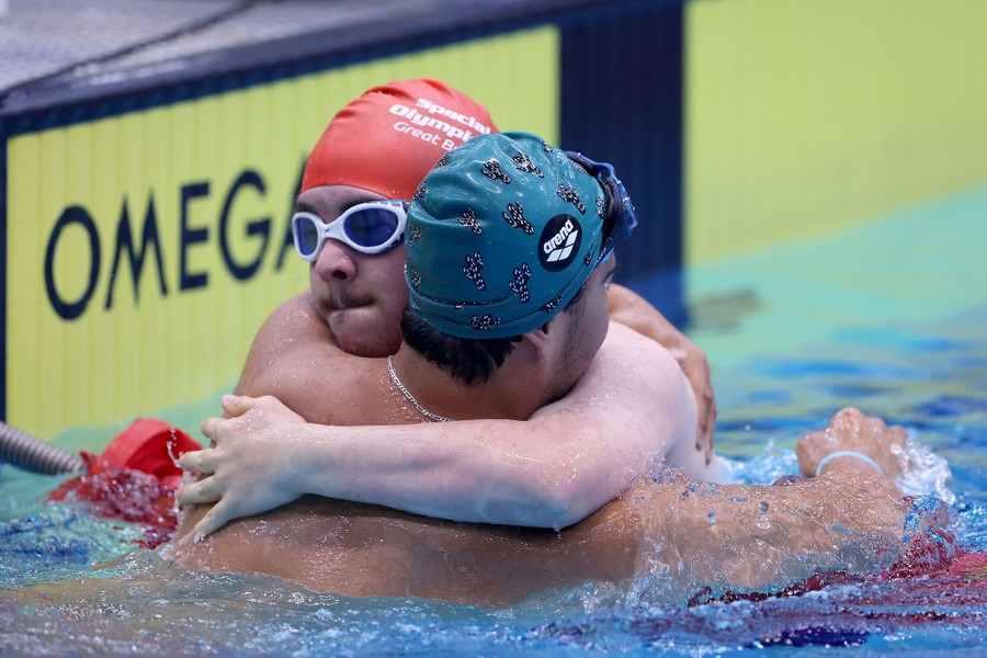 Two swimmers embrace in a pool after a race.