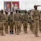 Soldiers standing at attention in front of pictures of state leaders