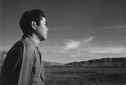 A pensive Japanese man looking out over a landscape in the western United States