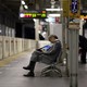 A man in business attire sleeps on a subway bench