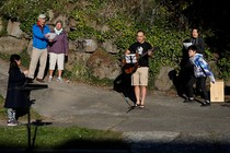 Yee Feng sings "Keep Your Head Up" by Andy Grammer with wife, Carolyn, and kids Ellie, 9, and Jediah, 11, during a neighborhood sing-along they have started doing each evening to connect with neighbors while social distancing during the coronavirus outbreak in Seattle.