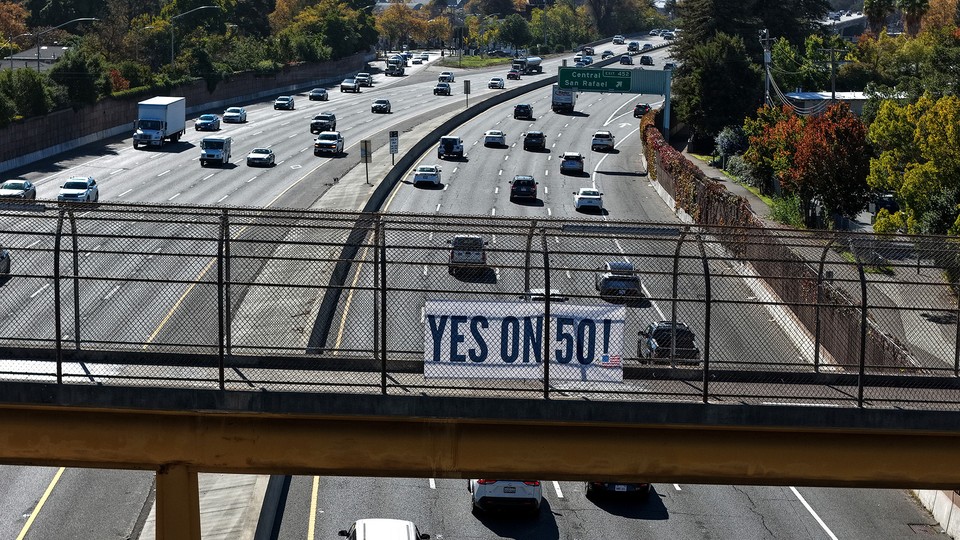 A "Yes on 50!" sign hangs over a freeway in California as cars drive below.