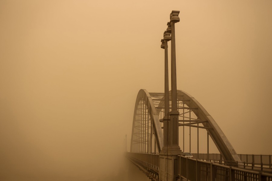 A bridge is seen during a very dusty day, appearing to fade into a cloud of dust.