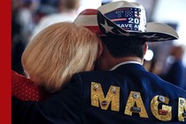 Photo showing woman resting her head on the shoulder of a man wearing "Trump 2024" cowboy hat and a jacket that reads MAGA