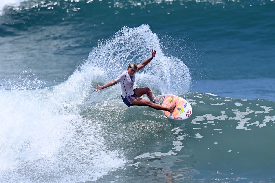A person surfs atop a medium-sized wave.