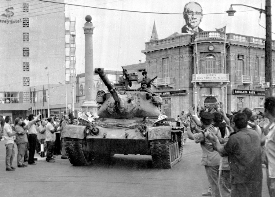People cheer as a tank drives past in a city street.