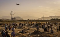 A military transport plane launches while stranded Afghans who cannot get into the airport to evacuate watch and wonder, in Kabul, Afghanistan