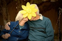 An older couple with a flower covering their faces