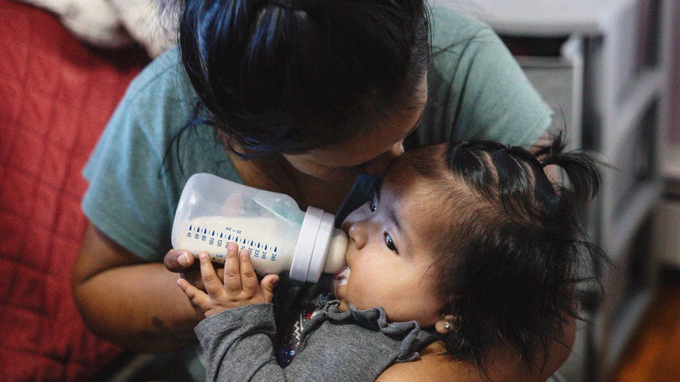 Photograph of a young child drinking from a bottle