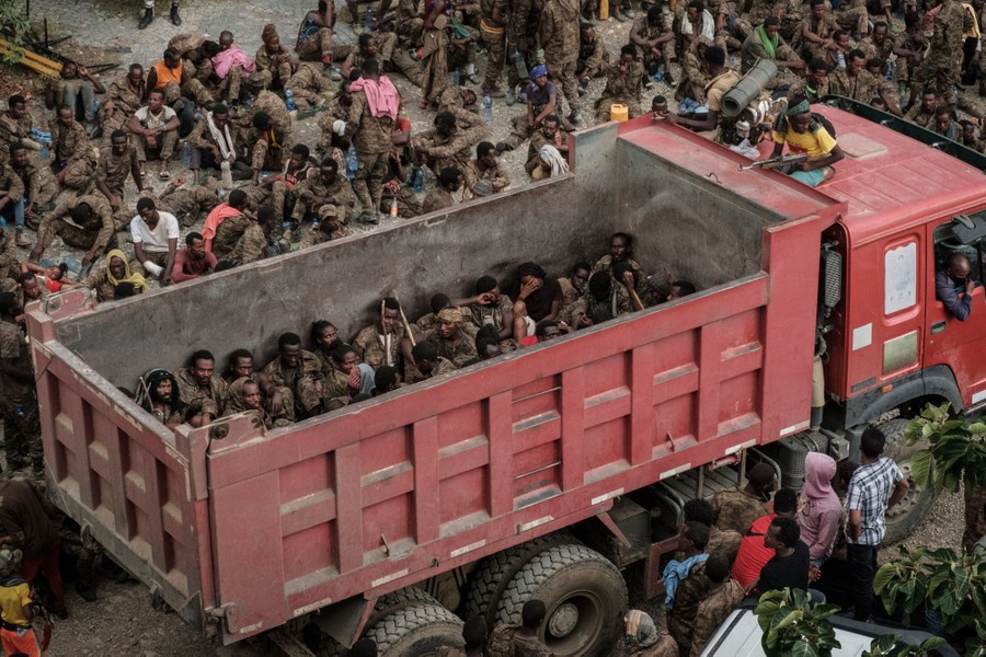 Dozens of soldiers are seen seated in the back of a large truck.
