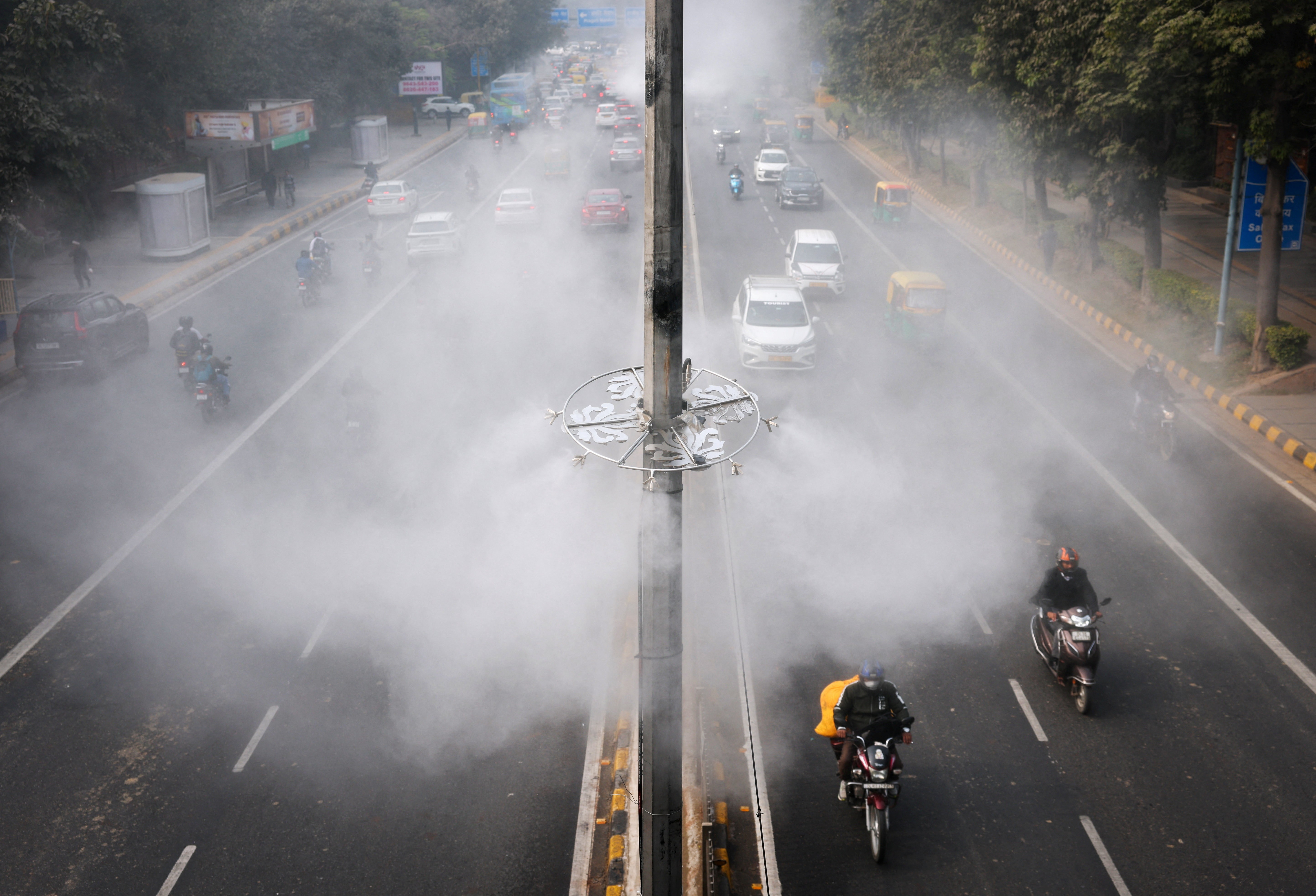 An elevated view of a highway with misters attached to poles in the median, spraying the air above traffic.