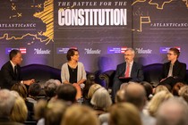 Four people sit on a stage in front of a sign that reads "The Battle for the Constitution"