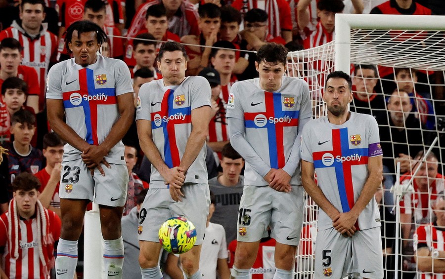 Four soccer players line up together and jump to block a free kick.