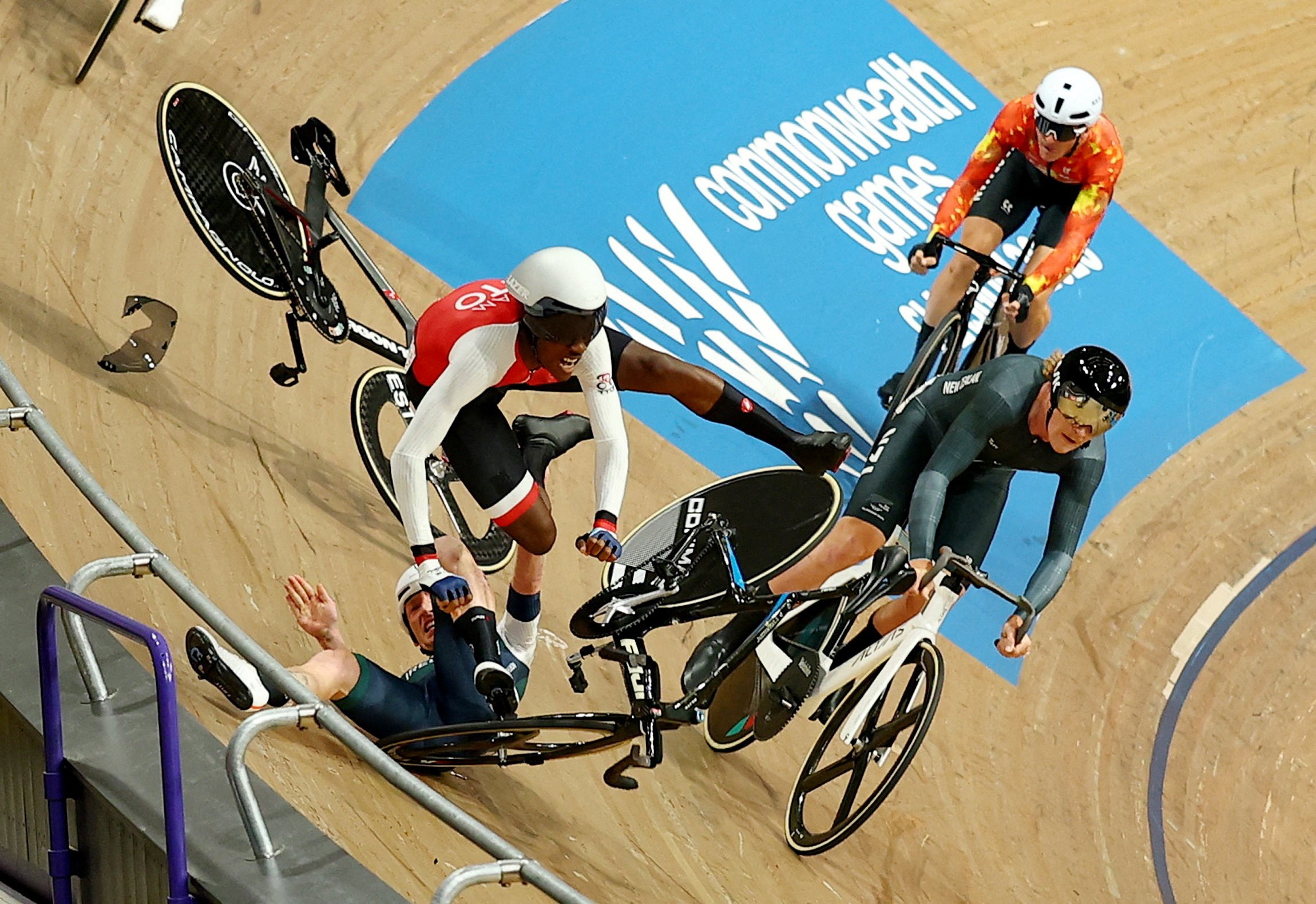 Two cyclists collide and fall on a steep indoor track during a race.