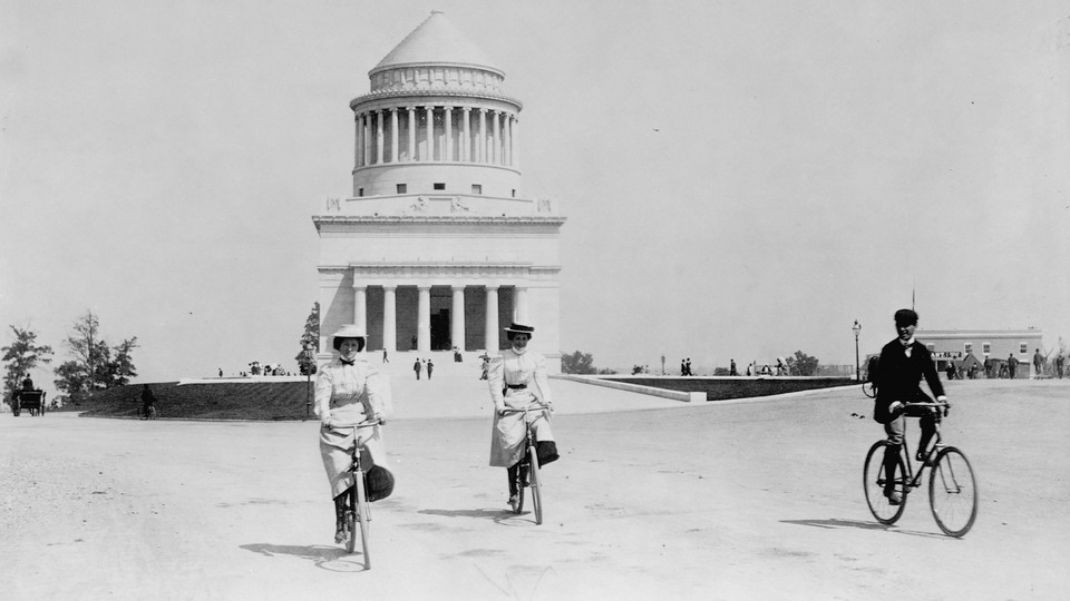 Two women and a man bicycle past Grant's Tomb in New York.