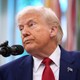 Donald Trump looks off to the side with a microphone in front of him