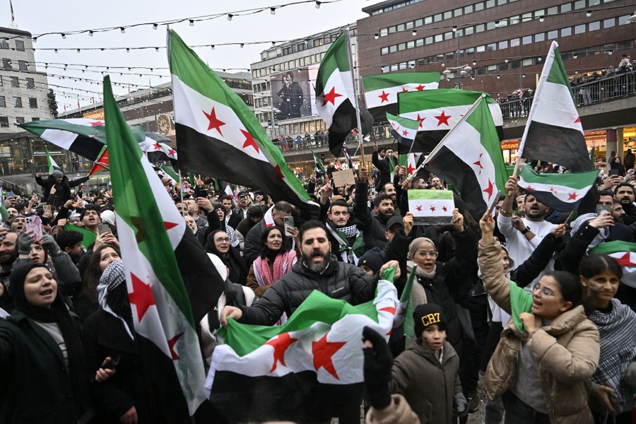 A crowd celebrates with flags in a city square.