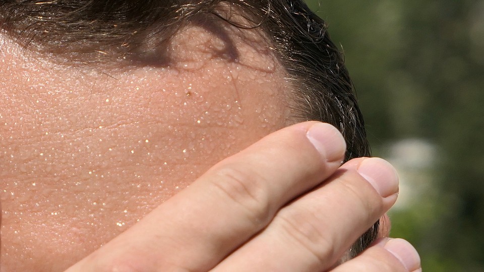 Close-up photograph of someone wiping their sweaty brow