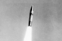A black-and-white photo of a missile blasting upwards through the air with flames propelling it toward its target