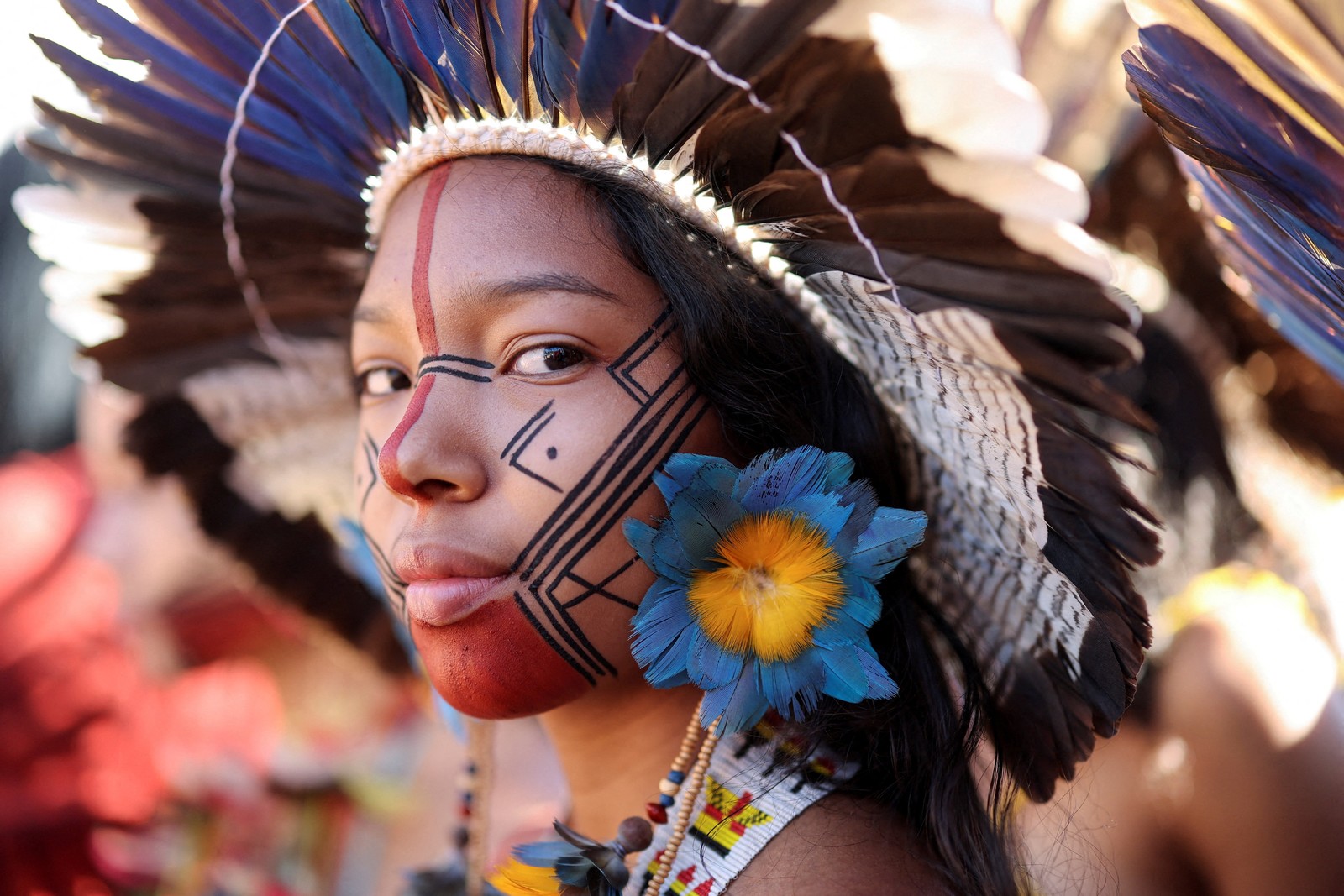 An indigenous woman wearing traditional makeup and a headdress, seen at a protest