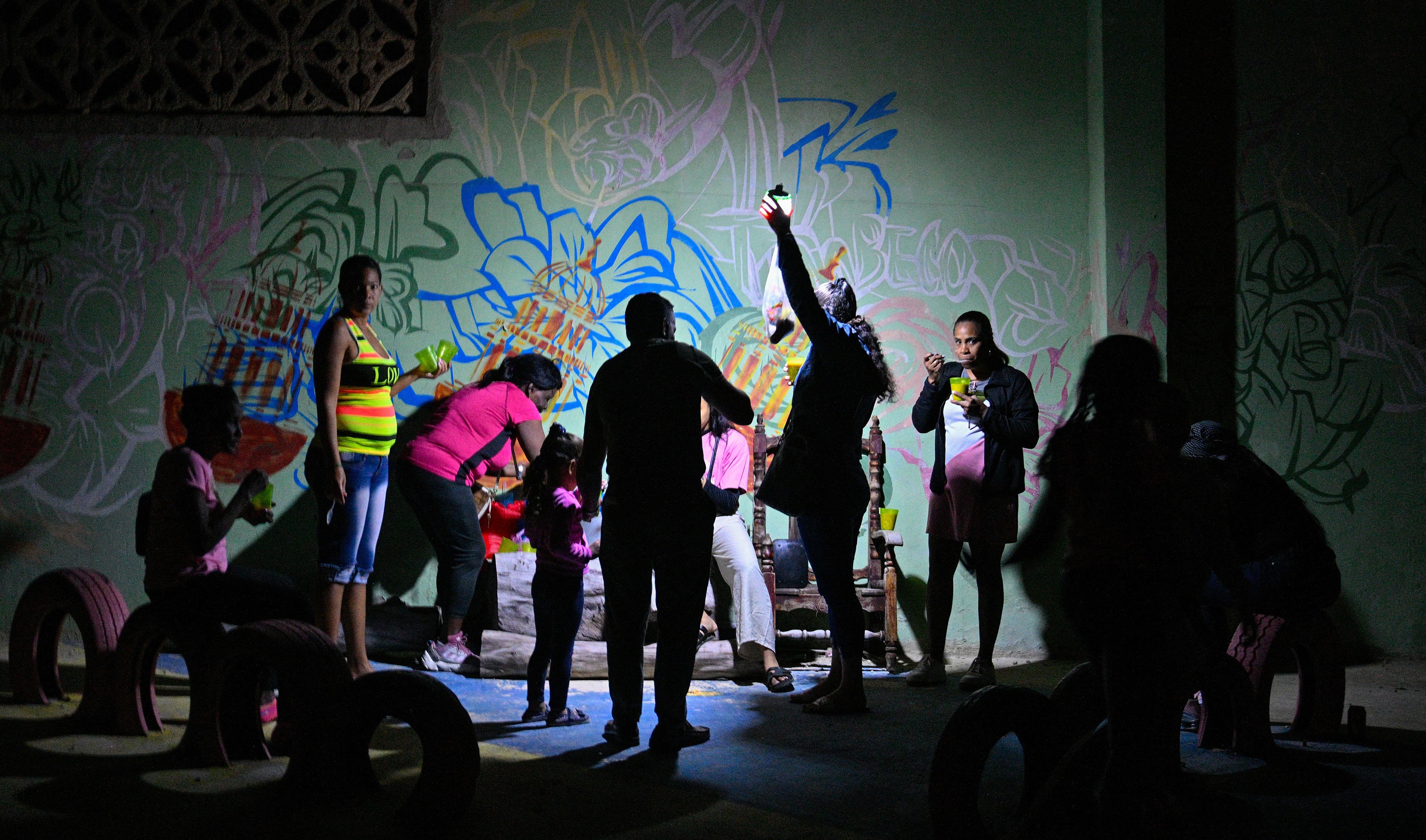 People celebrate during a party illuminated with portable lights during a blackout.
