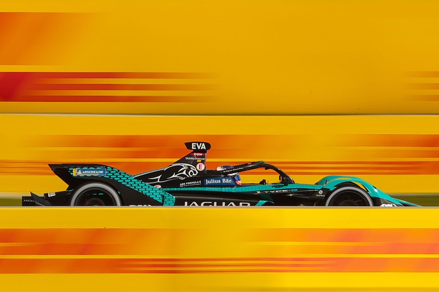 A race car speeds past red and yellow signage.