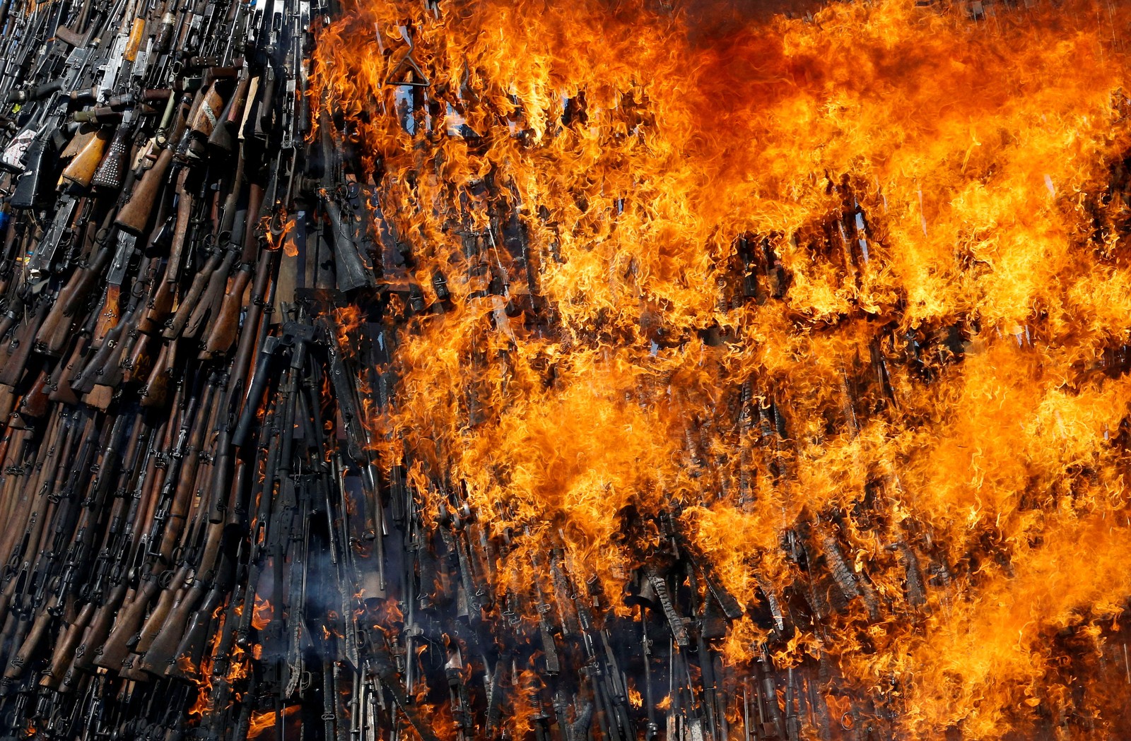 A huge stack of firearms goes up in flames.