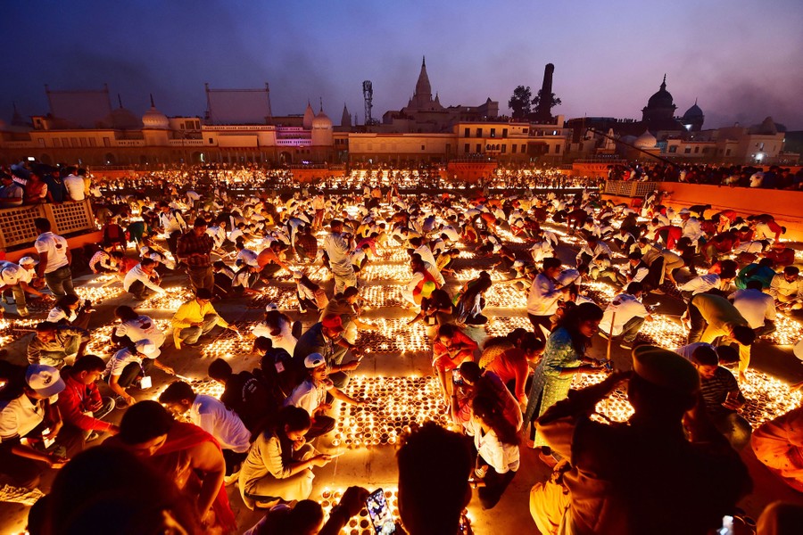 Thousands of lit candles illuminate people seated close together outside.
