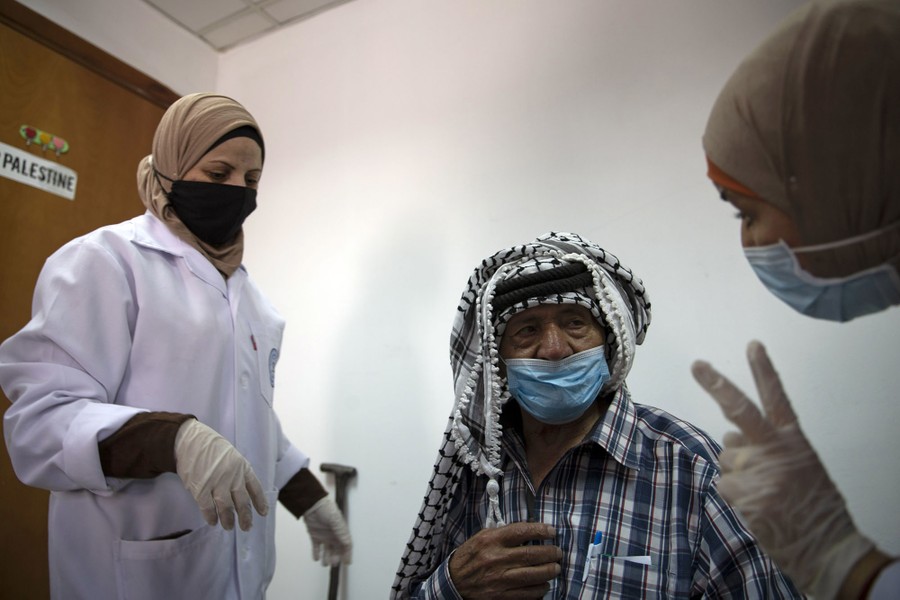 A masked man prepares for a vaccine shot.
