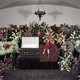 A casket at a funeral surrounded by flowers