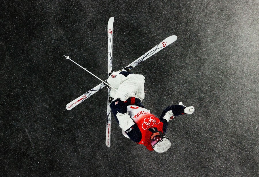 A skier is seen upside down, in mid-air, during a jump.