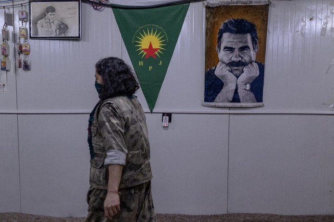 A woman in military fatigues walks past a poster of Abdullah Ocalan, the jailed founder of the Kurdistan Workers’ Party (PKK)